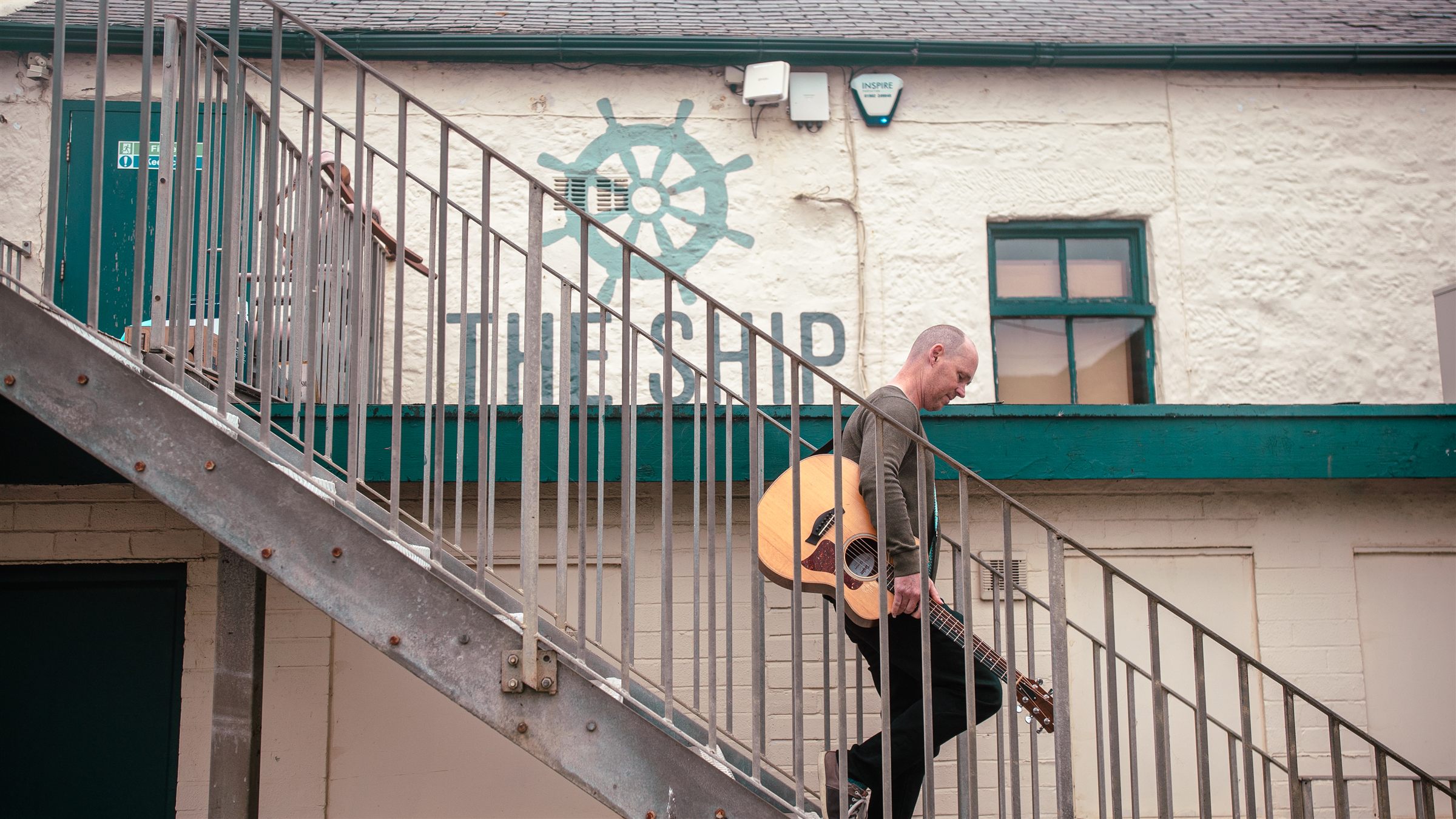 John walking down the stairs at The Ship, guitar in hand